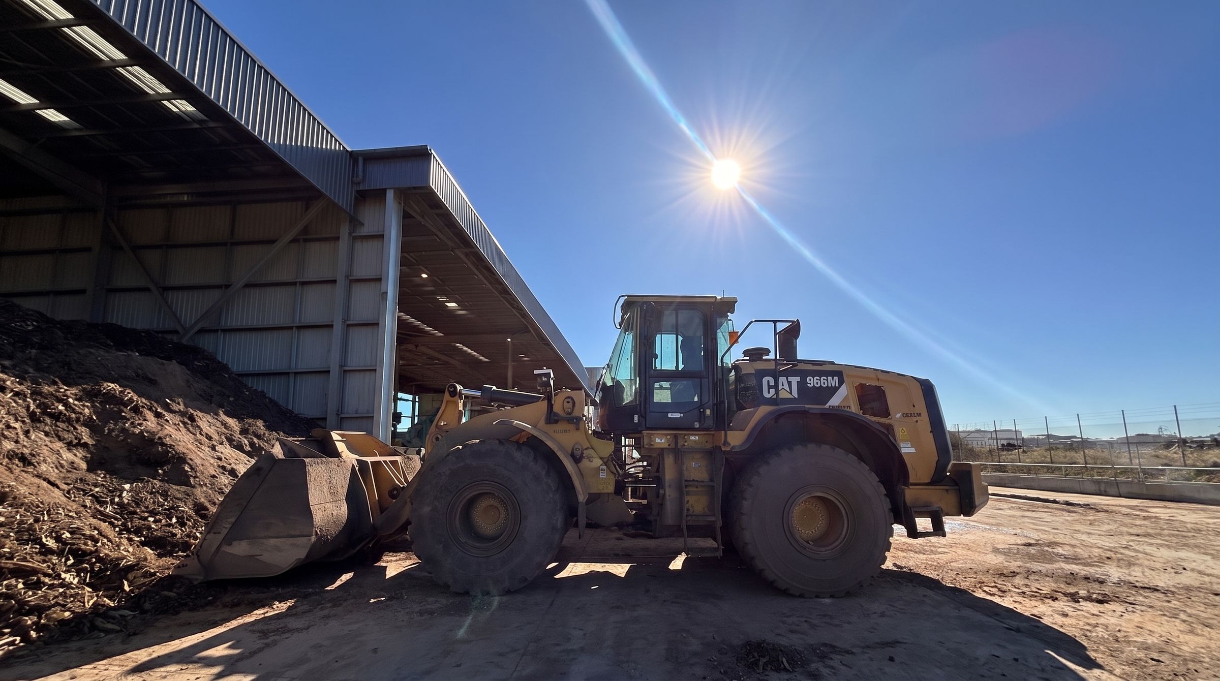 CAT 966M wheel loader parked under a shed on site